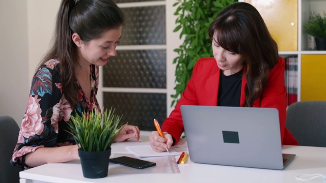 两名妇女坐在办公室的桌子上签署文件，起草法律文书视频素材