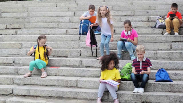 学生们带着书包和书坐在石阶上视频下载