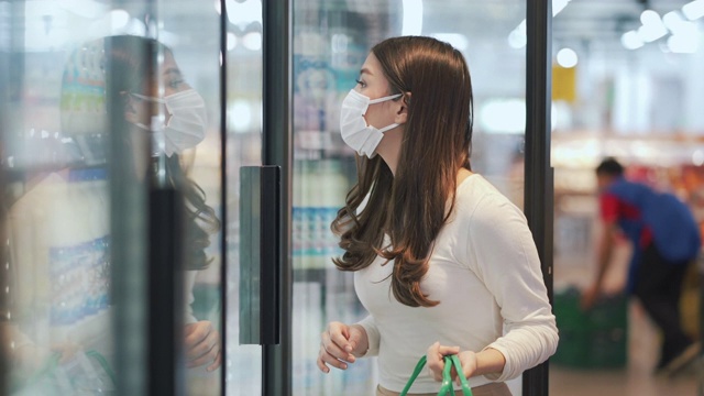 女人戴着口罩在超市购买冷冻产品视频素材