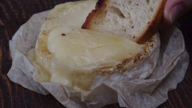 把烤面包蘸到卡门培尔奶酪里。极端特写镜头视频下载