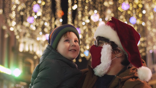 2019冠状病毒病大流行期间，一家人在城市街道上欣赏圣诞彩灯视频素材