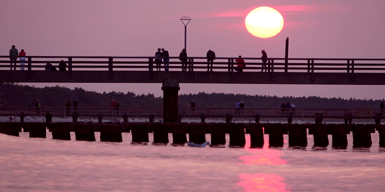 游客们在波罗的海海岸保护的码头上享受浪漫的日落视频素材