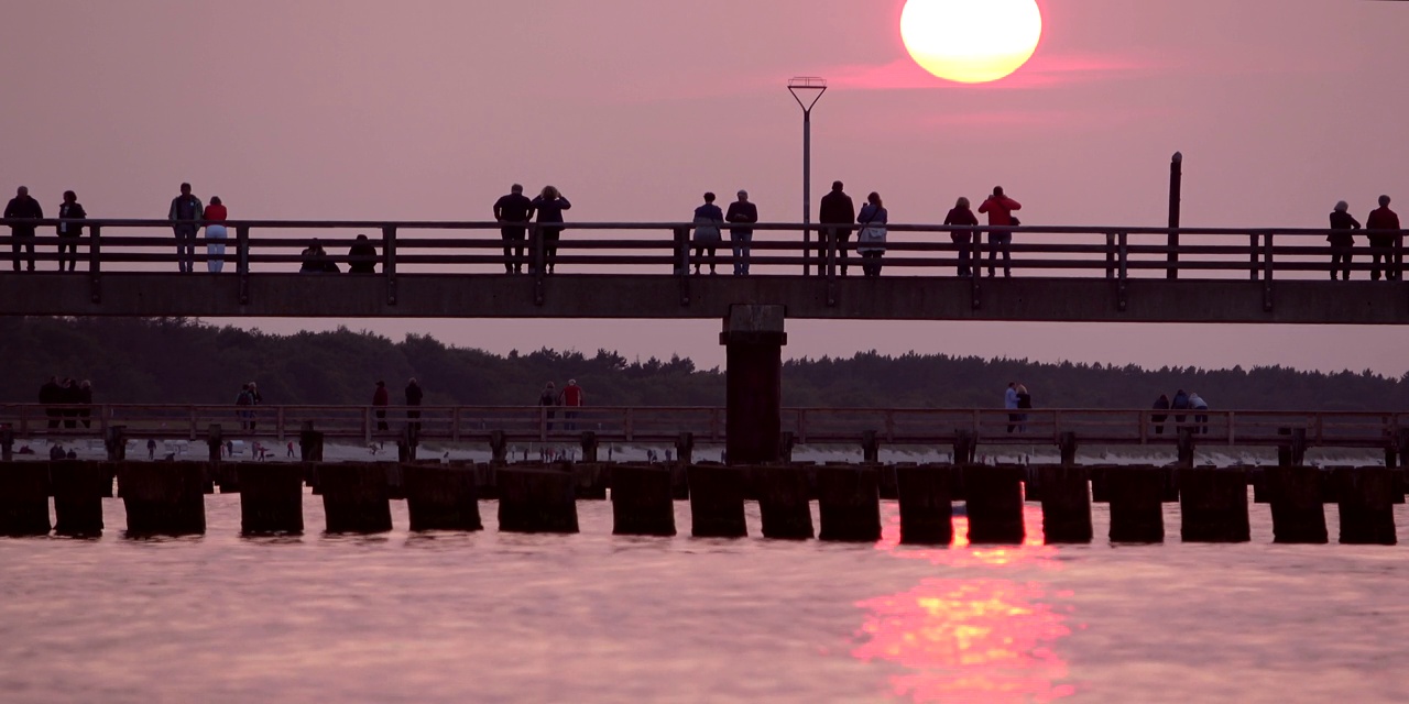 游客们在波罗的海海岸保护的码头上享受浪漫的日落视频素材