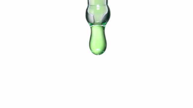 近距离和缓慢运动的绿色液体油滴从实验室移液管在白色背景视频素材
