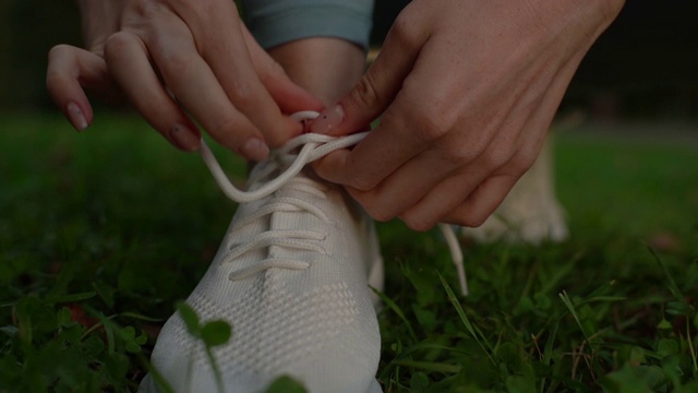 近距离观看，一个不认识的年轻女子在跑步前把鞋带系在运动鞋上。视频素材