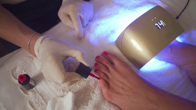 美容师在做足疗时涂粉色指甲油视频素材