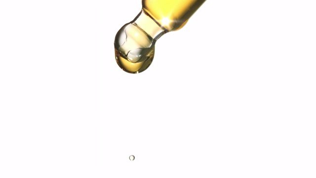 近距离和超级缓慢的运动液体油滴从实验室移液管在白色的背景。视频下载