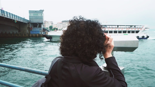 美丽的姑娘看风景用硬币双筒，加拉塔桥上的船在雨天通行视频下载