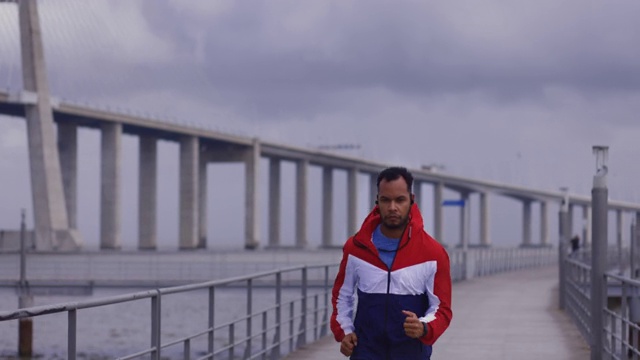 穿着风衣的非裔美国人在河城大桥附近跑步视频下载