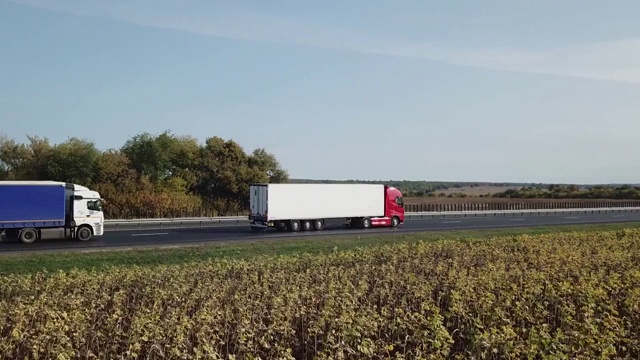 几辆卡车在高速公路上行驶，空中跟踪拍摄。提供物流服务视频下载