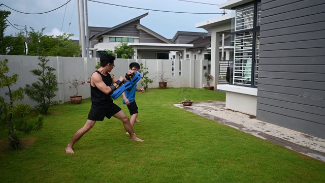 一位亚洲华人父亲在晚上的院子里训练他12岁的儿子跆拳道视频素材