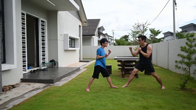 一位亚洲华人父亲在家门口训练他12岁的儿子晚上练武术视频素材