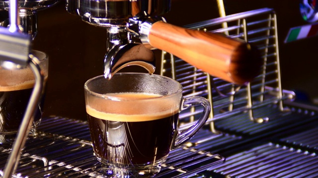 从咖啡机倒咖啡的特写。专业的咖啡酿造，使用过滤器支架。流动的现磨咖啡。早上喝烤黑咖啡。视频素材