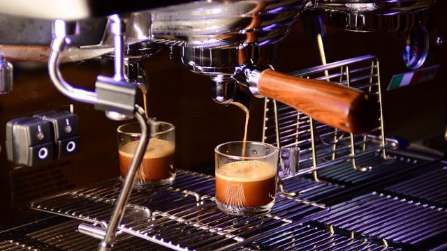 从咖啡机倒咖啡的特写。专业的咖啡酿造，使用过滤器支架。流动的现磨咖啡。早上喝烤黑咖啡。视频素材