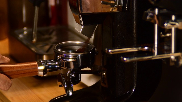 咖啡机正在准备新鲜的咖啡。滤纸架的特写，上面有咖啡机压碎的粉末。餐厅或酒吧的专业酿造。视频素材