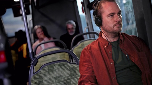 一名男子坐在公交车上戴着耳机听音乐视频素材