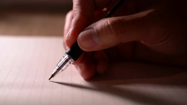 商人拿着笔在笔记本上写新约会的信息在组织者的概念，男性的手做笔记在个人纸计划办公桌上，近距离观看视频素材