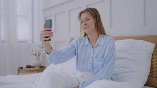 女商人在酒店里打视频电话。快乐的女孩躺在床上，和朋友视频通话。视频素材