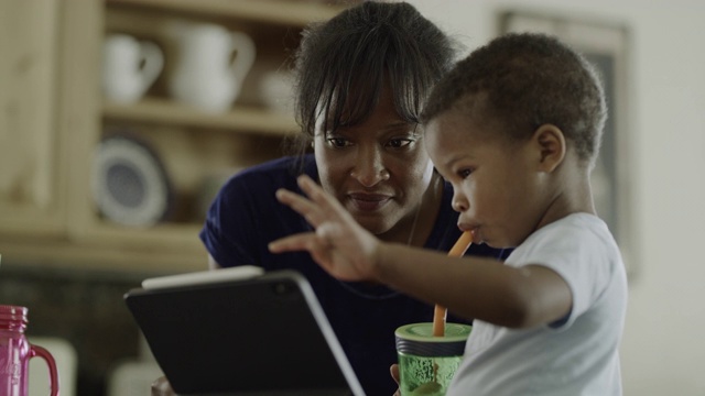 母亲指导兴奋的儿子使用数字平板电脑/ Orem，美国犹他州视频素材