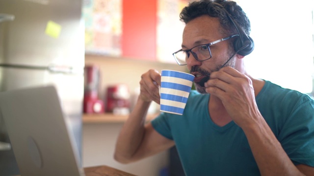 成年男性在家工作，在视频通话或客户通话时使用耳机视频素材