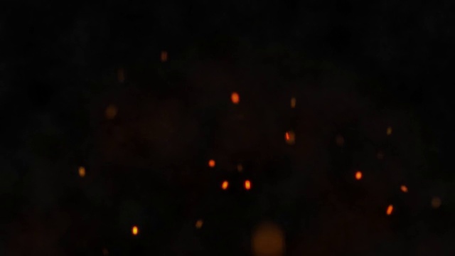熊熊燃烧的篝火在黑暗的背景上产生火花。从火中飞出余烬。4 k视频素材