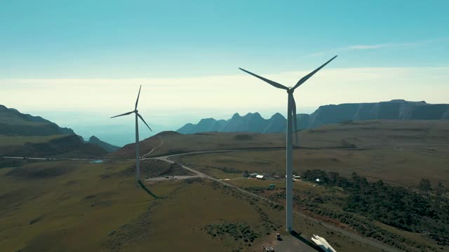 两座风力发电机位于靠近山脉和峡谷的高原顶部视频素材