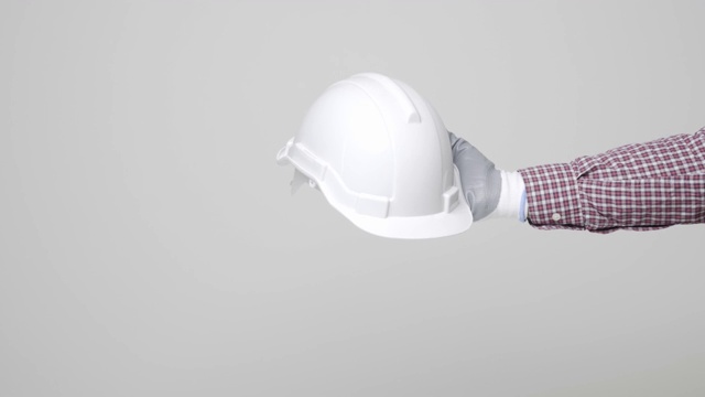 在孤立的白色背景上，机械工程师的手拿着安全帽。4 k决议。视频素材