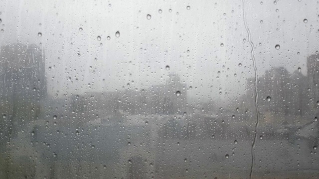 玻璃上水滴的特写。秋雨期间，大滴大滴地落在窗玻璃上，在白天倒映着天空。秋季和雨季概念。恶劣的天气视频素材