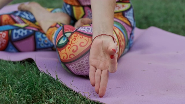 年轻女子在公园里摆莲花姿势冥想。手的特写镜头。视频下载