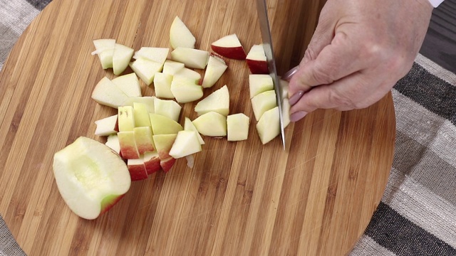 一个女人的手切红苹果在圆切板上俯视图视频下载