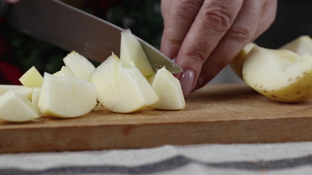 一个女人的手在圆形砧板上切红苹果的特写视频素材