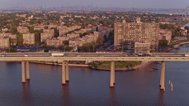鸟瞰图的比彻斯特住宅区在皇后区与曼哈顿在Throgs颈桥在日出的遥远的背景。无人机视频片段与向前摄像机运动视频素材