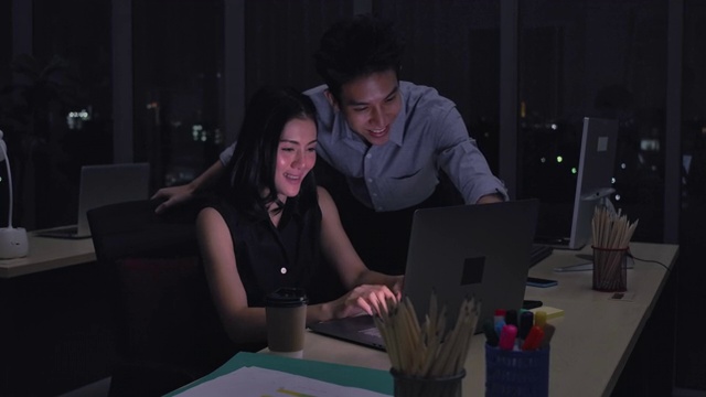 亚洲两名商人在晚上一起工作时使用电脑视频素材