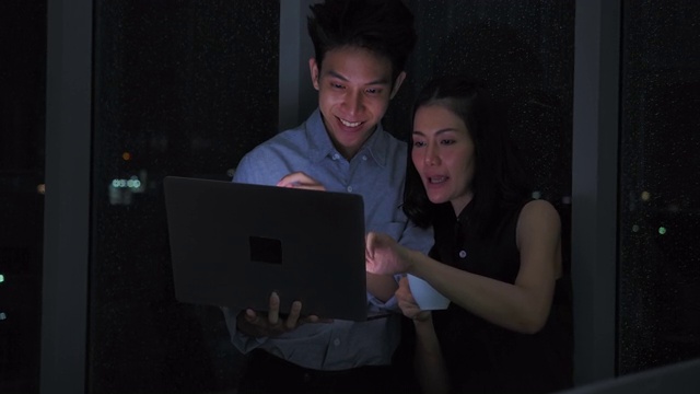 亚洲两名商人在晚上一起工作时使用电脑视频素材