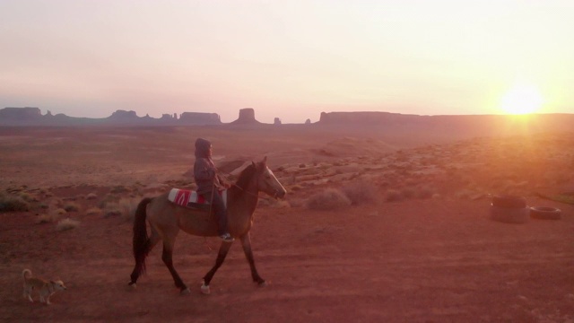 在亚利桑那州北部纪念碑谷部落公园附近的纳瓦霍保留区，年轻的美国土著纳瓦霍男孩骑着他的无鞍马视频下载