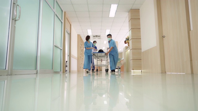 4K超高清缩小视角低角度拍摄:病人在医院轮床担架床上被医疗团队运送到医院走廊。视频素材