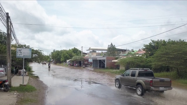 车辆和摩托车在大雨后穿过被水淹没的街道视频素材