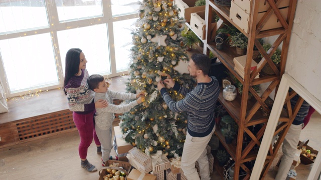 高角度观看母亲，父亲和儿子在家里装饰圣诞树视频素材