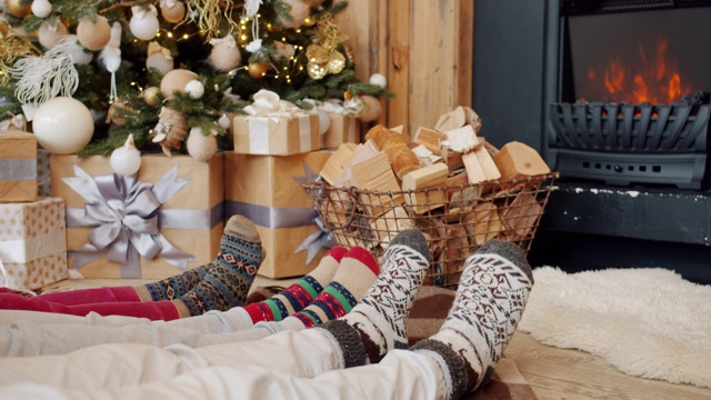 脚移动的特写，而人们放松在地板上舒适的房子与壁炉和圣诞树视频素材