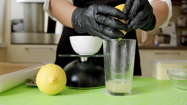 戴着黑手套的厨师挤柠檬，天然生料，特写。慢动作视频下载