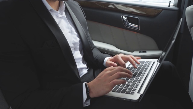 男士穿着正装，在豪华轿车里开着笔记本电脑视频素材