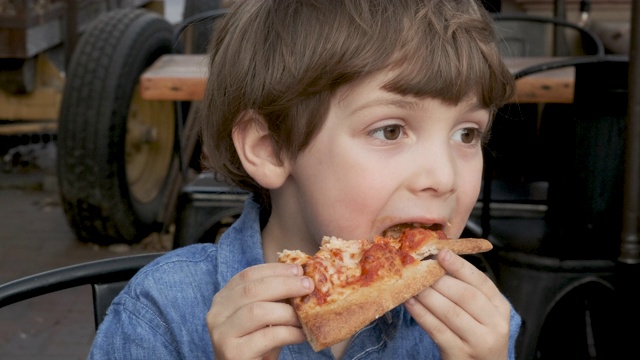 一个小男孩在吃披萨视频素材