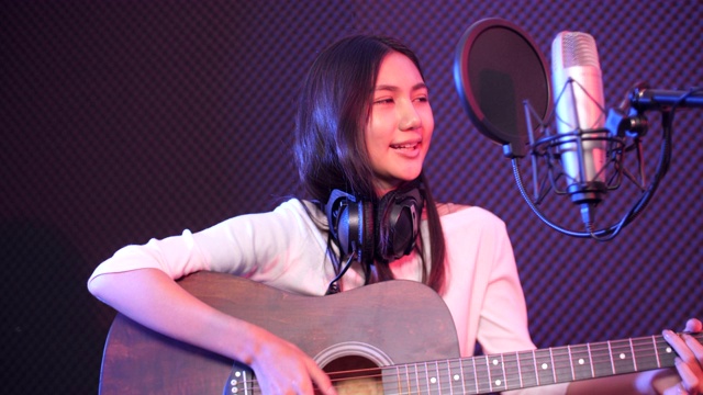 年轻的原声女歌手录制音乐与吉他在工作室，录音工作室的概念视频素材