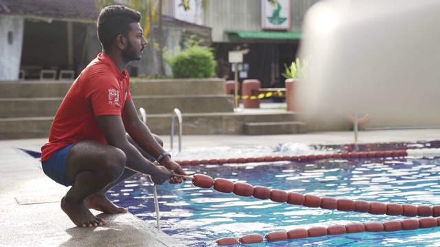 亚洲印度救生员在游泳池调整绳索准备视频下载