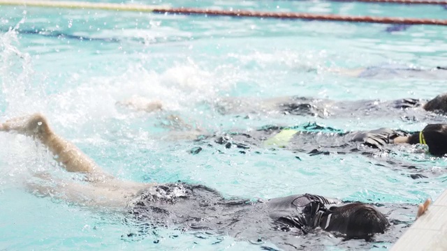 亚洲中国游泳运动员在游泳教练的指导下在泳池边练习腿溅水视频素材