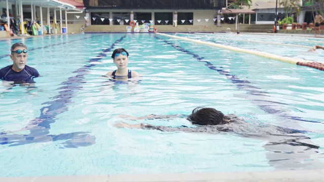 亚洲华裔男教练在游泳池向他的学生演示游泳技术视频素材