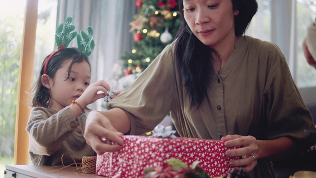 亚洲母亲和孩子的帮助包装圣诞礼物。视频下载