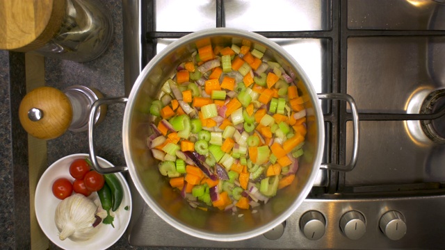 厨房铁架上的洋葱，芹菜和胡萝卜在平底锅里煮视频素材
