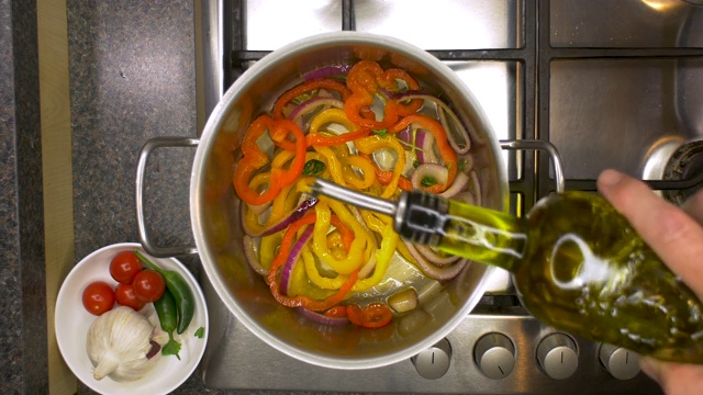 厨房铁架与橄榄油被添加到蔬菜在一个平底锅。视频素材