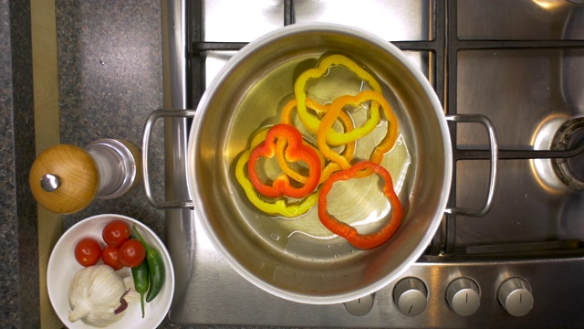 厨房铁架上的辣椒在平底锅里加热。视频素材